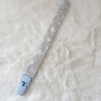 Tira de tecido cinzento com estrelas brancas e clip azul claro