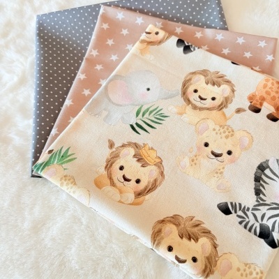 Três tecidos com padrões diferentes: animais da selva, estrelas e bolinhas sobre fundo branco felpudo