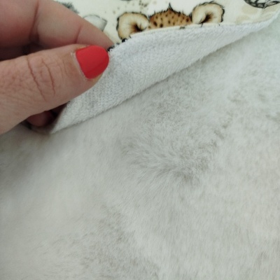 Detalhe de manta felpuda branca com padrão exterior e mão com unhas vermelhas segurando o tecido