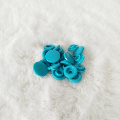 Botões de pressão azuis turquesa sobre tecido branco felpudo