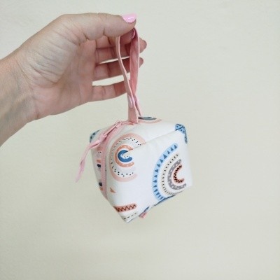 Bolsa pequena branca com padrões geométricos e cordão cor-de-rosa