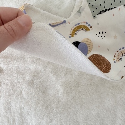 Manta para bebé branca e estampada com padrões coloridos.
