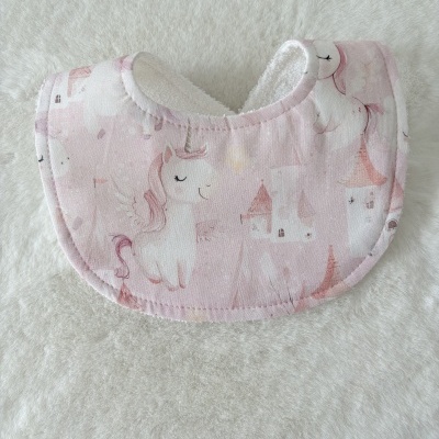 Babete cor-de-rosa com padrão de unicórnios e castelos