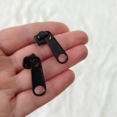 Puxadores de fecho éclair pretos com texto safe numa mão