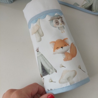 Travesseiro cilíndrico branco com estampas de raposa, coruja e cogumelos em tecido com borda azul clara.