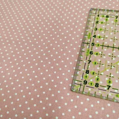 Tecido rosa com pontos brancos e régua transparente com marcações verdes
