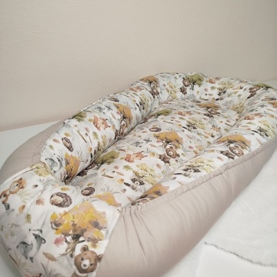 Ninho de bebé com estampado de animais da floresta e laterais bege claro.