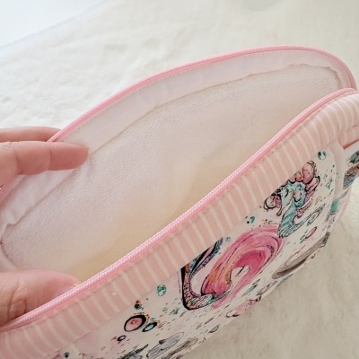 Necessaire retangular com padrão colorido e interior branco macio.