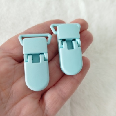Dois clips de plástico azul claro segurados numa mão