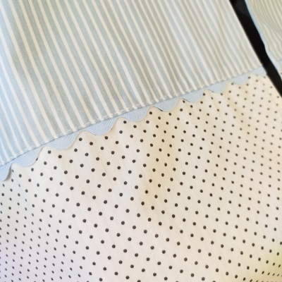 tecido com riscas azuis e brancas e bolinhas pretas em fundo branco com detalhe ondulado azul