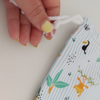 Mão a segurar cordão de máscara de tecido com padrão colorido