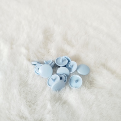 Botões de pressão azuis claros sobre superfície branca felpuda