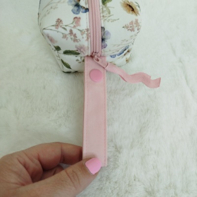 Necessaire floral com fecho rosa e alça com botão de pressão