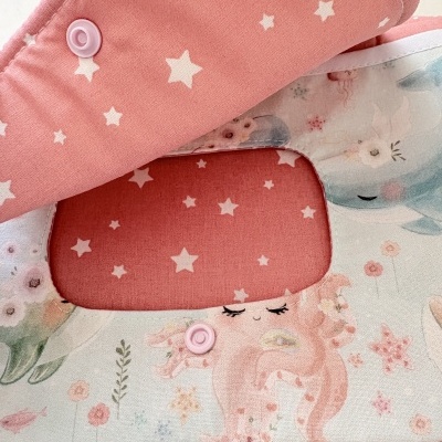 Babete infantil rosa com estrelas e ilustrações de sereia e golfinho