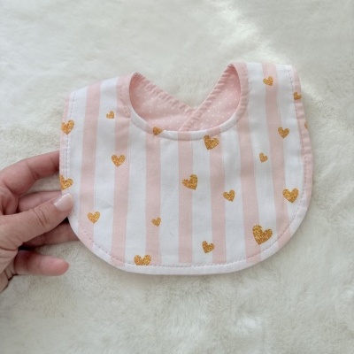 Babete de bebé com riscas rosa e corações dourados