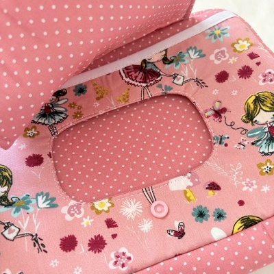 Produto em tecido rosa com padrão de bolinhas brancas e ilustrações de meninas e flores