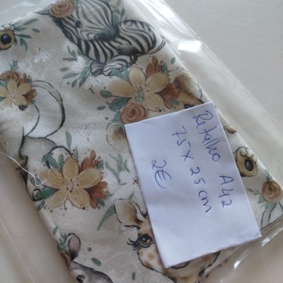 Retalho de tecido com padrão de flores e animais embalado em saco plástico com etiqueta manuscrita