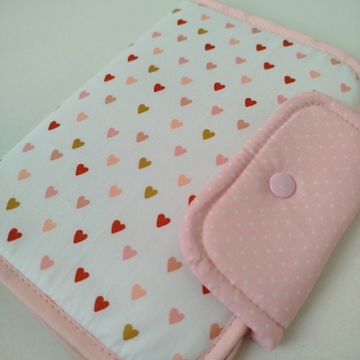 Estojo de tecido branco com corações coloridos e fecho rosa com padrão de pontos brancos