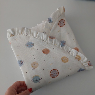 Manta de tecido branco com padrão de planetas sorridentes e borda franzida
