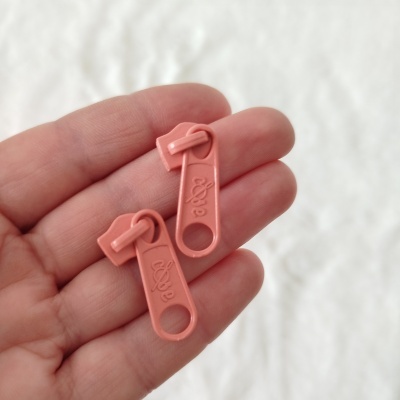 Dois puxadores de fecho éclair cor de rosa em plástico na mão