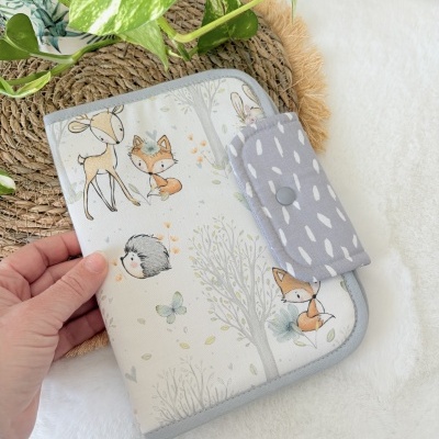 Capa de tecido com padrão de animais da floresta e fecho em botão cinzento