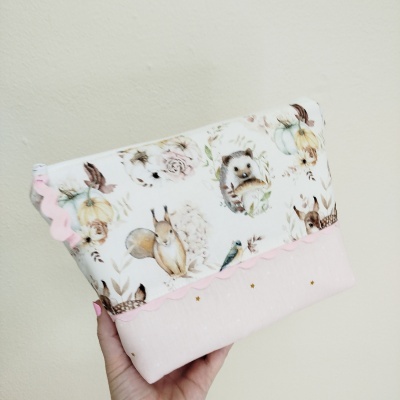 Bolsa ou estojo em tecido com padrão de animais e flores, cor-de-rosa e branco.