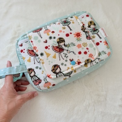 Bolsa de tecido com padrão de fadas e flores coloridas com botão azul