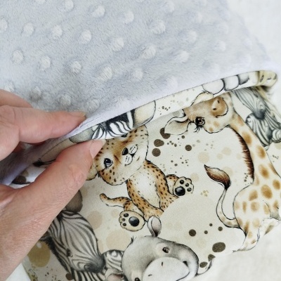 Cobertor cinza com bolinhas em relevo e estampado de animais de desenho animado.