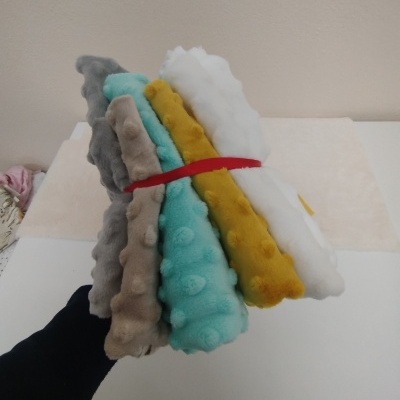 Conjunto de mantas coloridas com textura pontilhada amarradas com fita vermelha