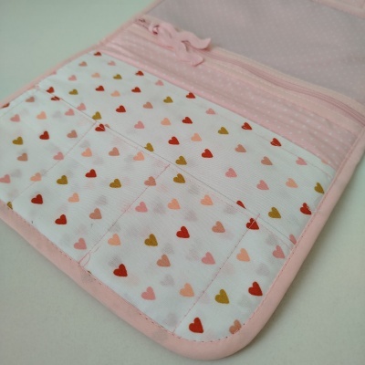 Estojo rosa com bolso em rede e interior com padrão de corações coloridos