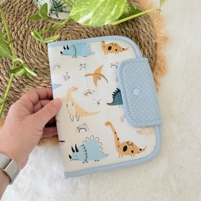 Estojo de tecido com padrão de dinossauros e fecho azul com bolinhas brancas