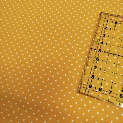 Tecido amarelo com bolinhas brancas e régua transparente amarela sobre ele