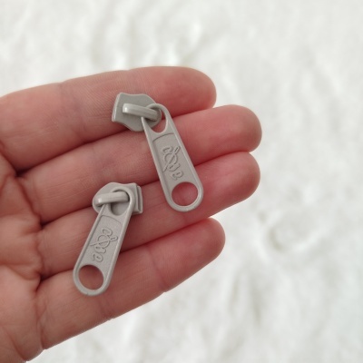 Dois puxadores de fecho éclair cinzentos na mão