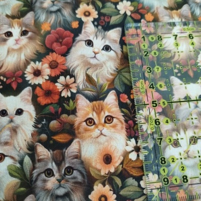 Tecido estampado com gatos e flores e régua transparente ao lado.