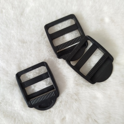 Três fivelas de plástico preto retangulares sobre superfície felpuda branca