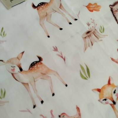 Tecido branco com padrão de animais e elementos naturais, etiqueta 'Mamã produtos'