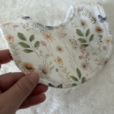 Babete para bebé branco com padrão de flores e folhas coloridas