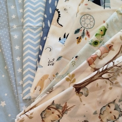 Tecidos com padrões infantis, cores pastel e diferentes texturas.