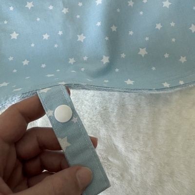 Tecido azul claro com estrelas brancas e aba com botão de pressão