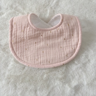 Babete cor-de-rosa com detalhes dourados e interior branco colocado sobre superfície branca macia