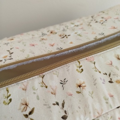 Bolsa ou mala bege com padrão floral pastel e fecho de correr