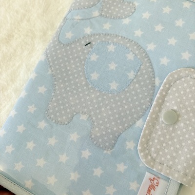 Capa de tecido azul com padrão de estrelas e elefante cinza aplicada.