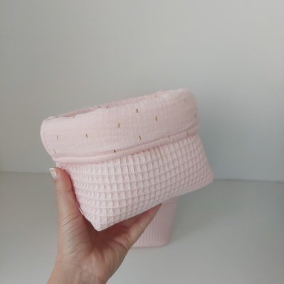 Mala rosa quadrada com textura em relevo e detalhes dourados, segurada por uma mão