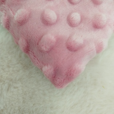 Almofada cor-de-rosa felpuda com pequenos nodos sobre tecido creme felpudo