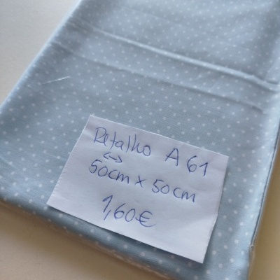 Tecido azul claro com bolinhas brancas e etiqueta com preço e tamanho