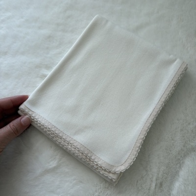Guardanapo branco com borda bege decorativa em fundo branco felpudo