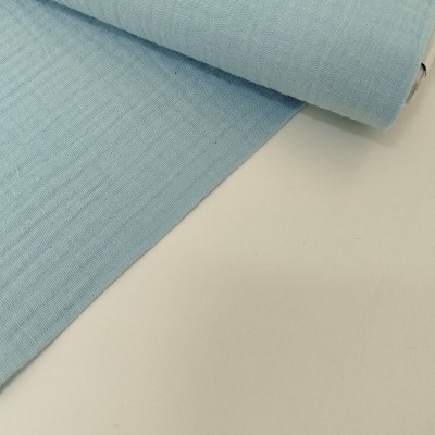 Rolo de tecido azul claro com textura ondulada sobre superfície branca