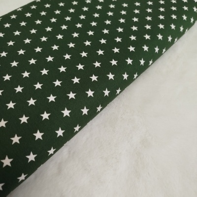 Tecido verde com padrão de estrelas brancas sobre superfície branca