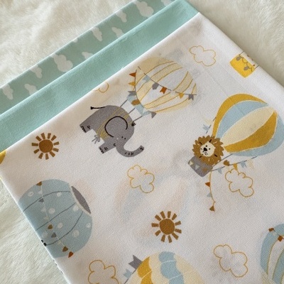 Três tecidos de algodão coloridos para criança com padrões de balões e animais.