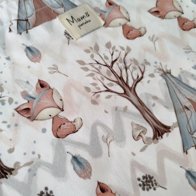 Tecido branco com padrão de raposas, árvores e tendas, etiqueta 'Mamá patinhas'.